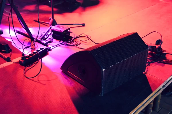 escenario-de-concierto-bajo-una-luz-roja-con-muchos-cables-soportes-de-microfono-y-un-gran-altavoz-en-el-suelo